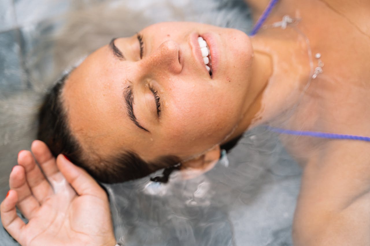Close-up of a relaxed woman floating in water with eyes closed and enjoying serene moment.